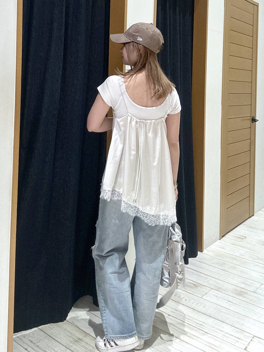 シルバー系のトートバッグ、ブルー系のデニムパンツ、ベージュ系のキャミソールを着用したレディースの春コーディネートの3枚目の写真