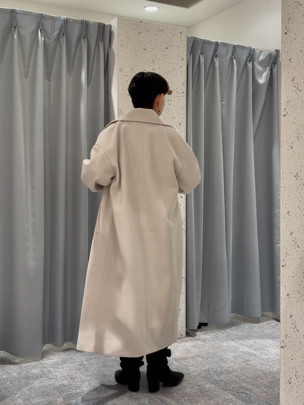 ホワイト系のチェスターコート、ブラウン系のニット/セーター、ブラック系のブーツを着用したレディースの秋コーディネートの2枚目の写真