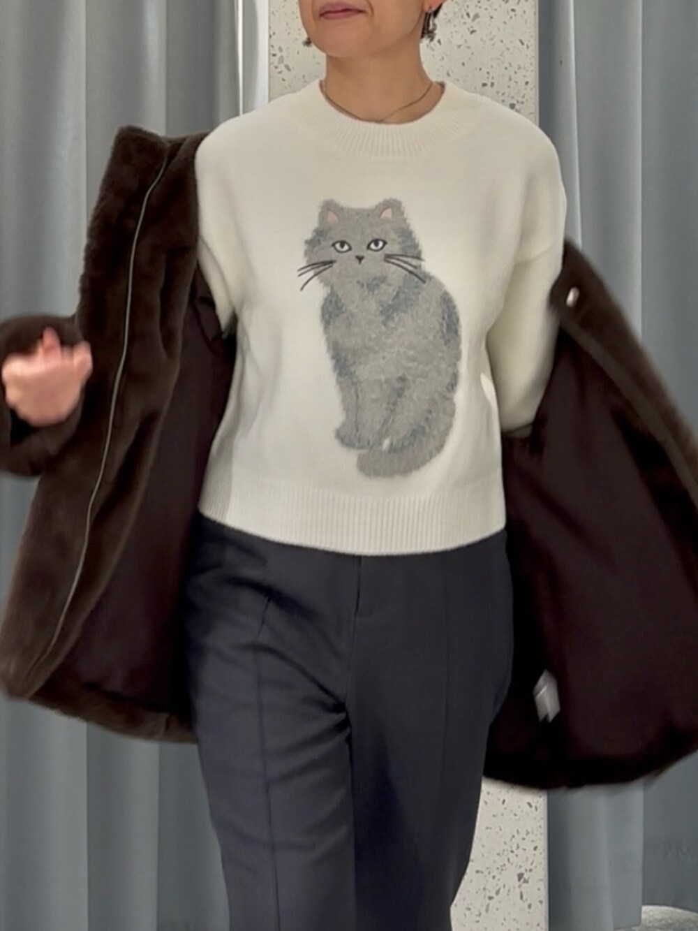 グレー系のスラックス、ホワイト系のニット/セーター、ブラウン系のノーカラーコートを着用したレディースの冬コーディネートの5枚目の写真