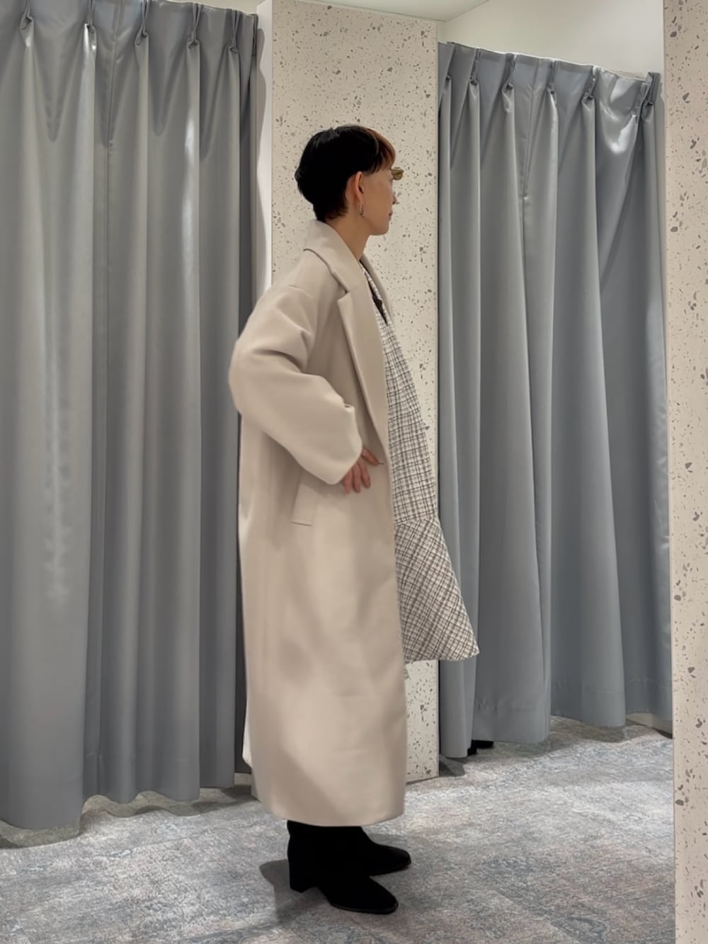 ホワイト系のチェスターコート、ブラウン系のニット/セーター、ブラック系のブーツを着用したレディースの秋コーディネートの3枚目の写真