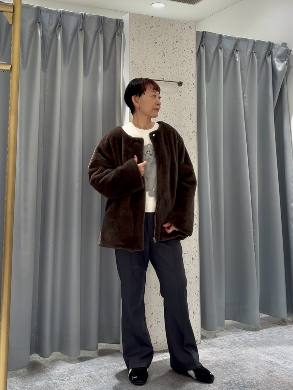 グレー系のスラックス、ホワイト系のニット/セーター、ブラウン系のノーカラーコートを着用したレディースの冬コーディネートの2枚目の写真