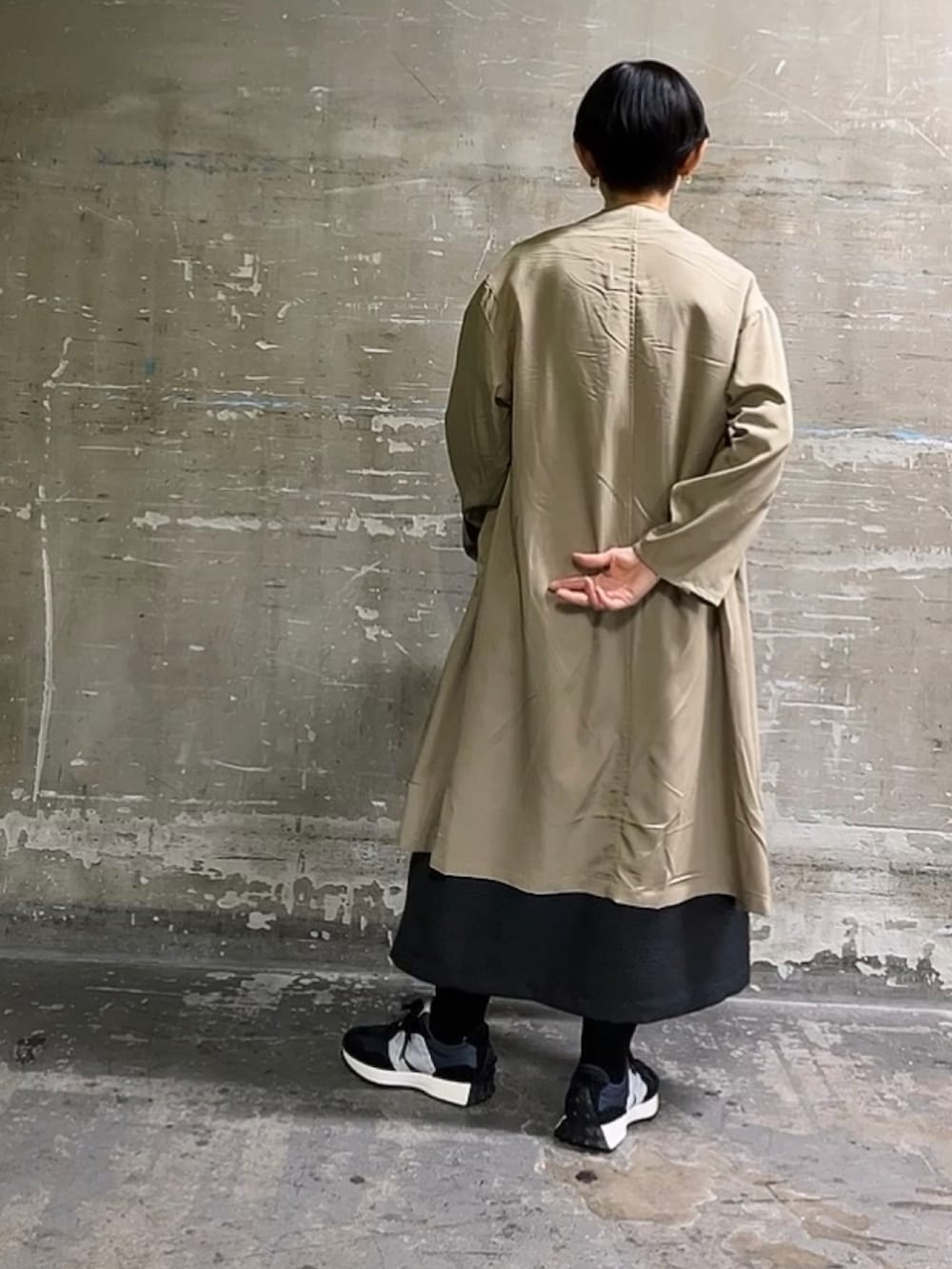 ベージュ系のノーカラーコート、ホワイト系のTシャツ/カットソー、ブラック系のワンピースを着用したレディースの冬コーディネートの3枚目の写真