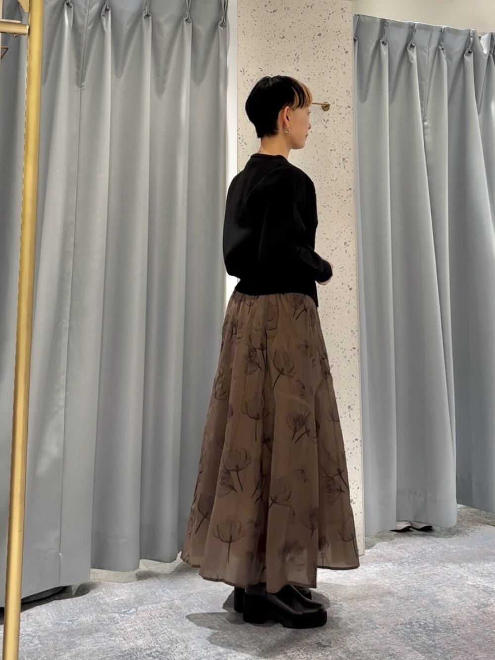 ブラック系のカーディガン/ボレロ、ブラック系のブーツ、イエロー系のスカートを着用したレディースの秋コーディネートの3枚目の写真