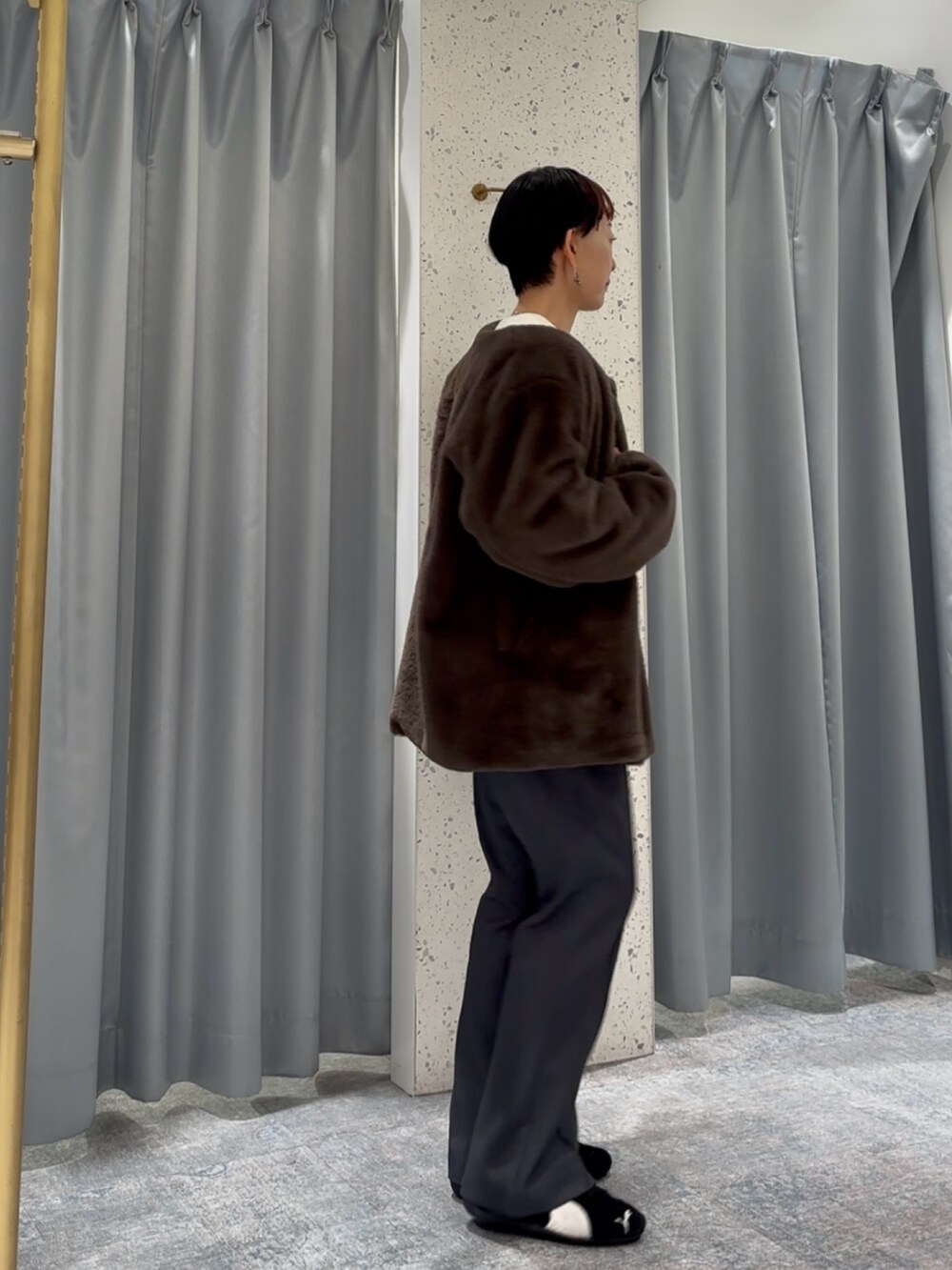 グレー系のスラックス、ホワイト系のニット/セーター、ブラウン系のノーカラーコートを着用したレディースの冬コーディネートの3枚目の写真