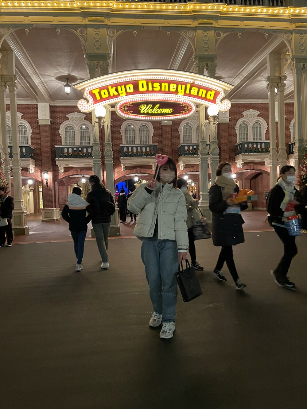 ベージュ系のダウンジャケット/コート、ブラック系のショルダーバッグ、ブルー系のデニムパンツを着用したレディースの冬コーディネートの2枚目の写真