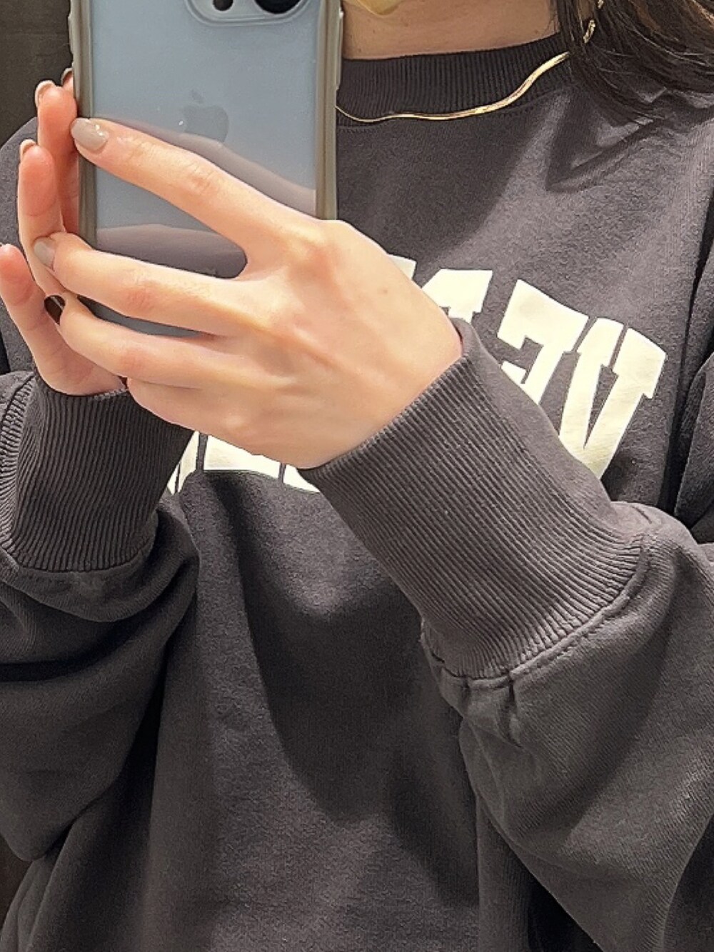 グレー系のスウェット、ホワイト系のスカート、ゴールド系のネックレスを着用したレディースの冬コーディネートの2枚目の写真