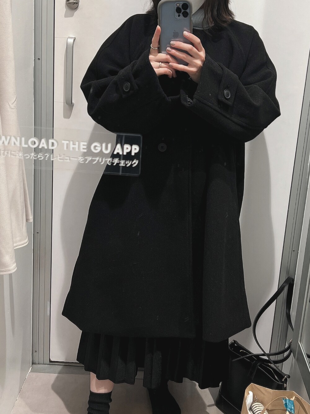 ブルー系のニット/セーター、ブラック系のスカート、ブラック系のノーカラーコートを着用したレディースの冬コーディネートの2枚目の写真