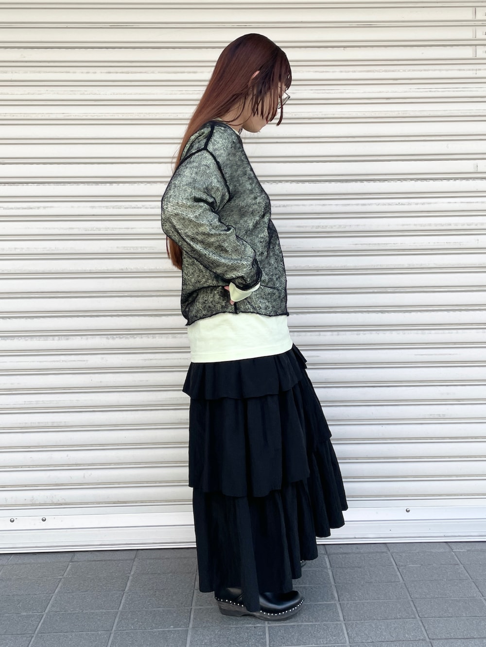 グリーン系のTシャツ/カットソー、ブラック系のスカート、ブラック系のニット/セーターを着用したレディースの秋コーディネートの2枚目の写真