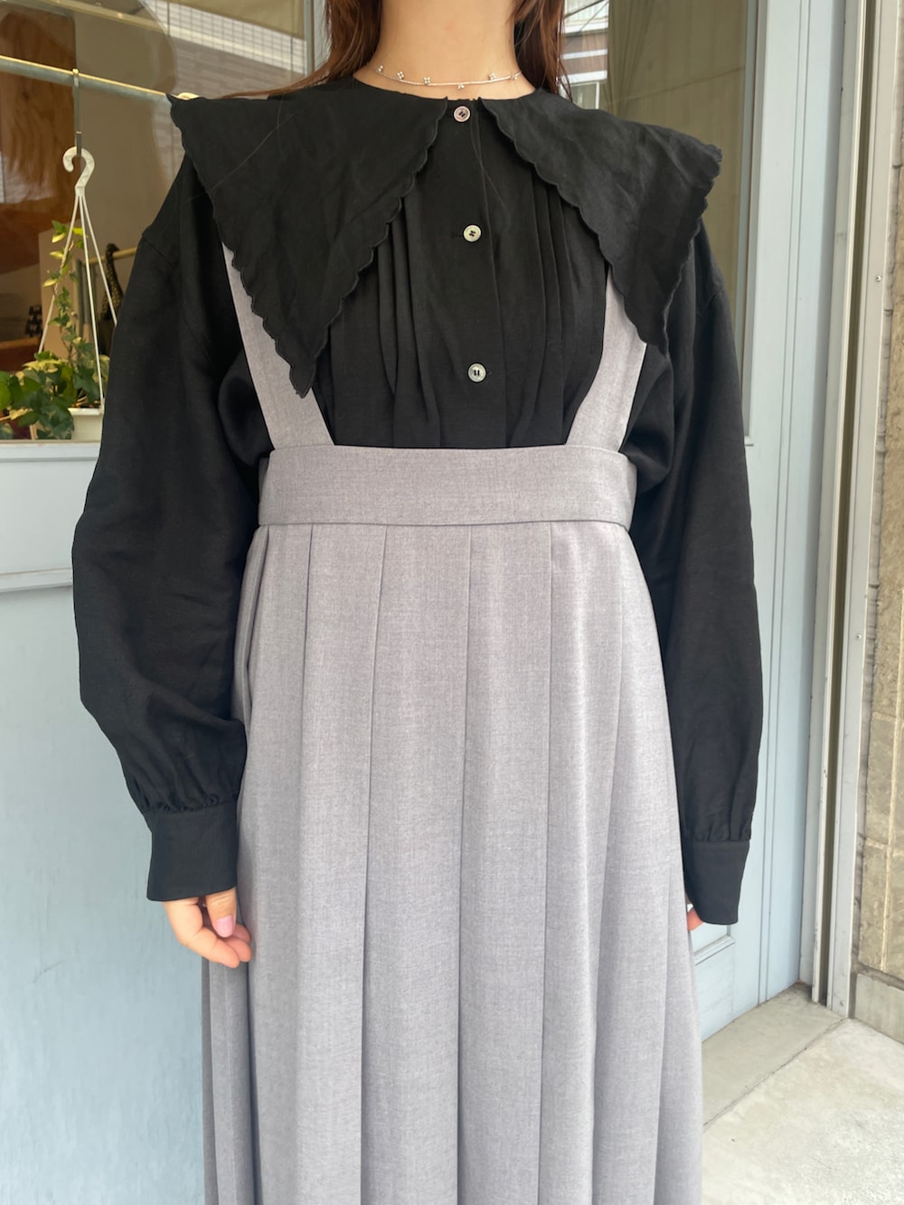 ブラック系のシャツ/ブラウス、グレー系のジャンパースカート、ベージュ系のキャップを着用したレディースの春コーディネートの3枚目の写真