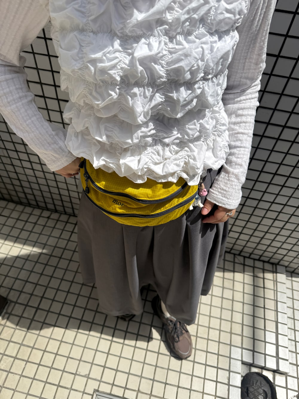 ホワイト系のTシャツ/カットソー、グレー系のスカート、ブラウン系のスニーカーを着用したレディースの夏コーディネートの2枚目の写真
