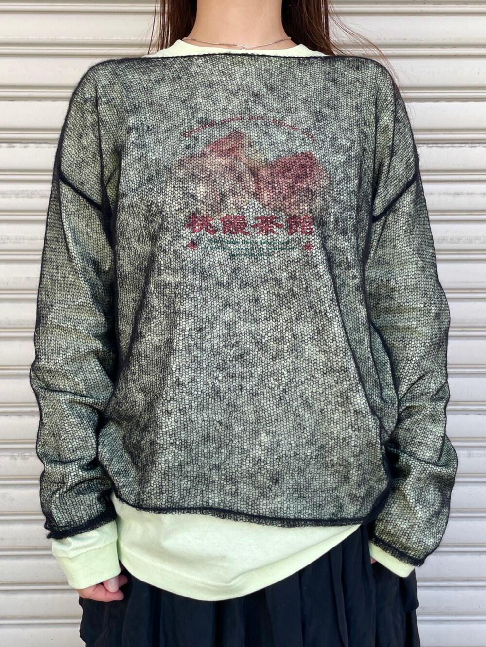 グリーン系のTシャツ/カットソー、ブラック系のスカート、ブラック系のニット/セーターを着用したレディースの秋コーディネートの3枚目の写真
