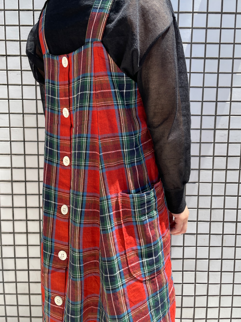 レッド系のワンピース、ブラック系のニット/セーター、ホワイト系のソックス/靴下を着用したレディースの春コーディネートの3枚目の写真