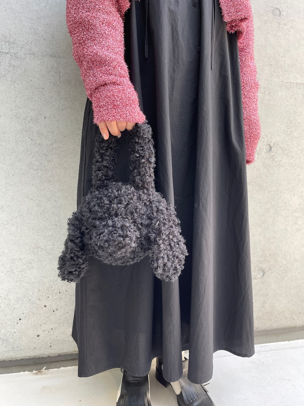 ブラック系のワンピース、ピンク系のニット/セーター、ブラック系のハンドバッグを着用したレディースの秋コーディネートの3枚目の写真