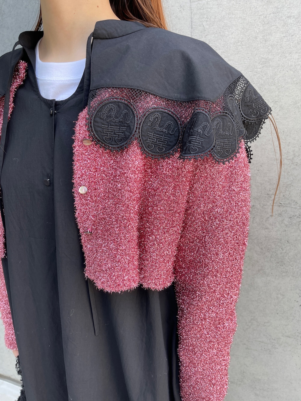 ブラック系のワンピース、ピンク系のニット/セーター、ブラック系のハンドバッグを着用したレディースの秋コーディネートの2枚目の写真