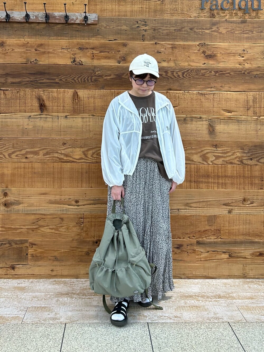 ベージュ系のスカート、ホワイト系のジャケット/アウター、ブラウン系のTシャツ/カットソーを着用したレディースの夏コーディネートの2枚目の写真