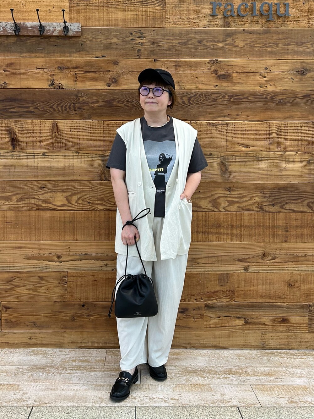 グレー系のTシャツ/カットソー、ホワイト系のベスト、ブラック系のバッグを着用したレディースの春コーディネートの2枚目の写真