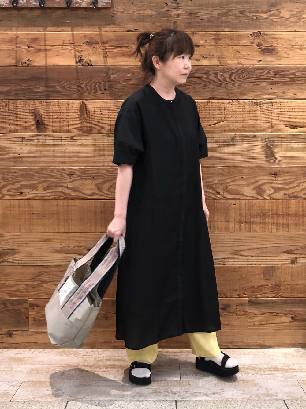 ブラック系のワンピース、イエロー系のその他パンツ、ベージュ系のトートバッグを着用したレディースの夏コーディネートの3枚目の写真