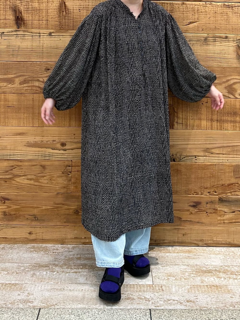 ブラック系のワンピース、ブルー系のデニムパンツを着用したレディースの春コーディネートの2枚目の写真