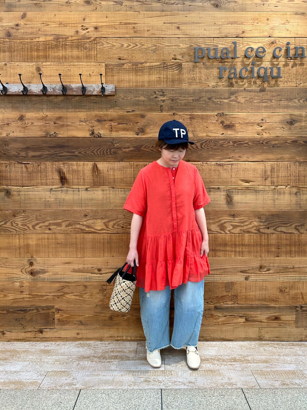 オレンジ系のシャツ/ブラウス、ベージュ系のハンドバッグ、ブルー系のデニムパンツを着用したレディースの春コーディネートの2枚目の写真