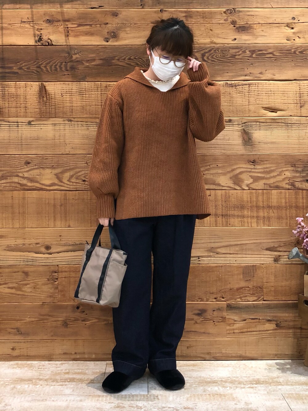 イエロー系のニット/セーター、ブルー系のデニムパンツ、ベージュ系のトートバッグを着用したレディースの冬コーディネートの2枚目の写真