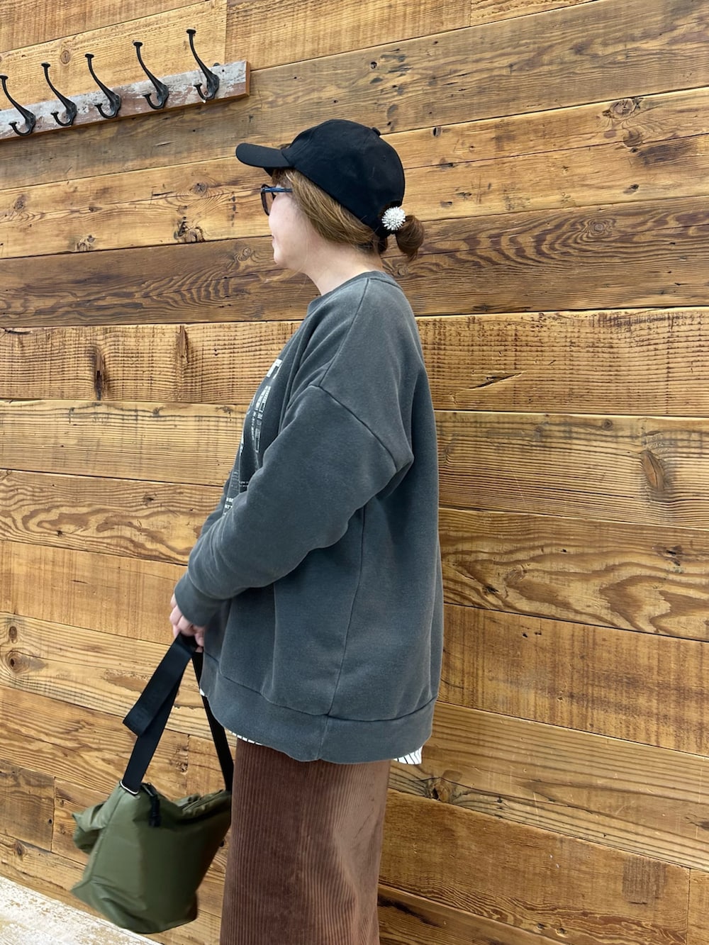 グレー系のトップス、ブラウン系のスカート、グリーン系のショルダーバッグを着用したレディースの冬コーディネートの3枚目の写真