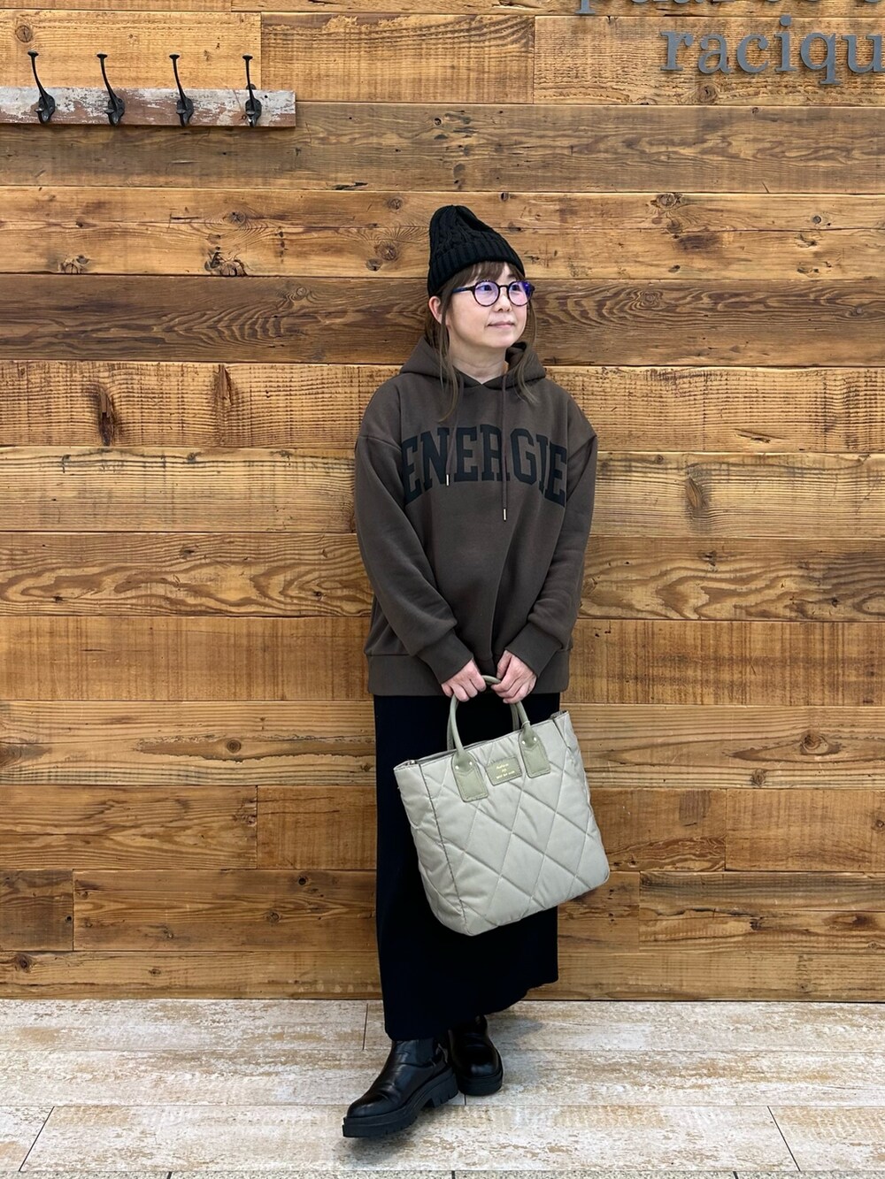 ブラウン系のパーカー、ベージュ系のトートバッグ、ブラック系のスカートを着用したレディースの冬コーディネートの2枚目の写真