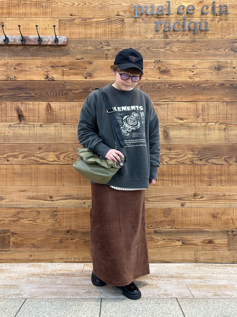 グレー系のトップス、ブラウン系のスカート、グリーン系のショルダーバッグを着用したレディースの冬コーディネートの2枚目の写真