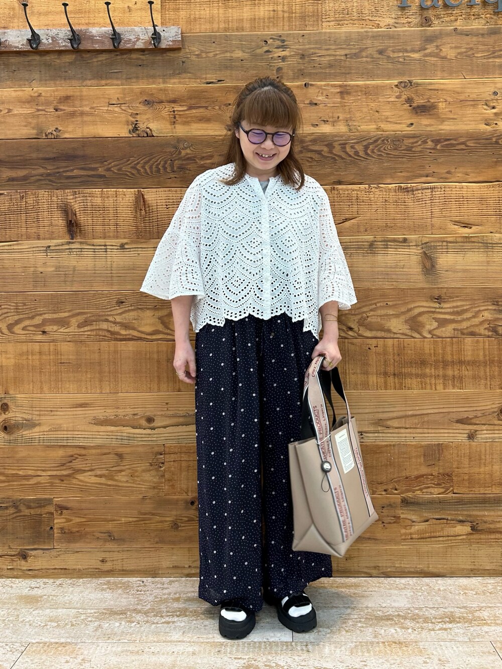 ホワイト系のシャツ/ブラウス、ブラック系のサンダル、ブルー系のパンツを着用したレディースの夏コーディネートの2枚目の写真