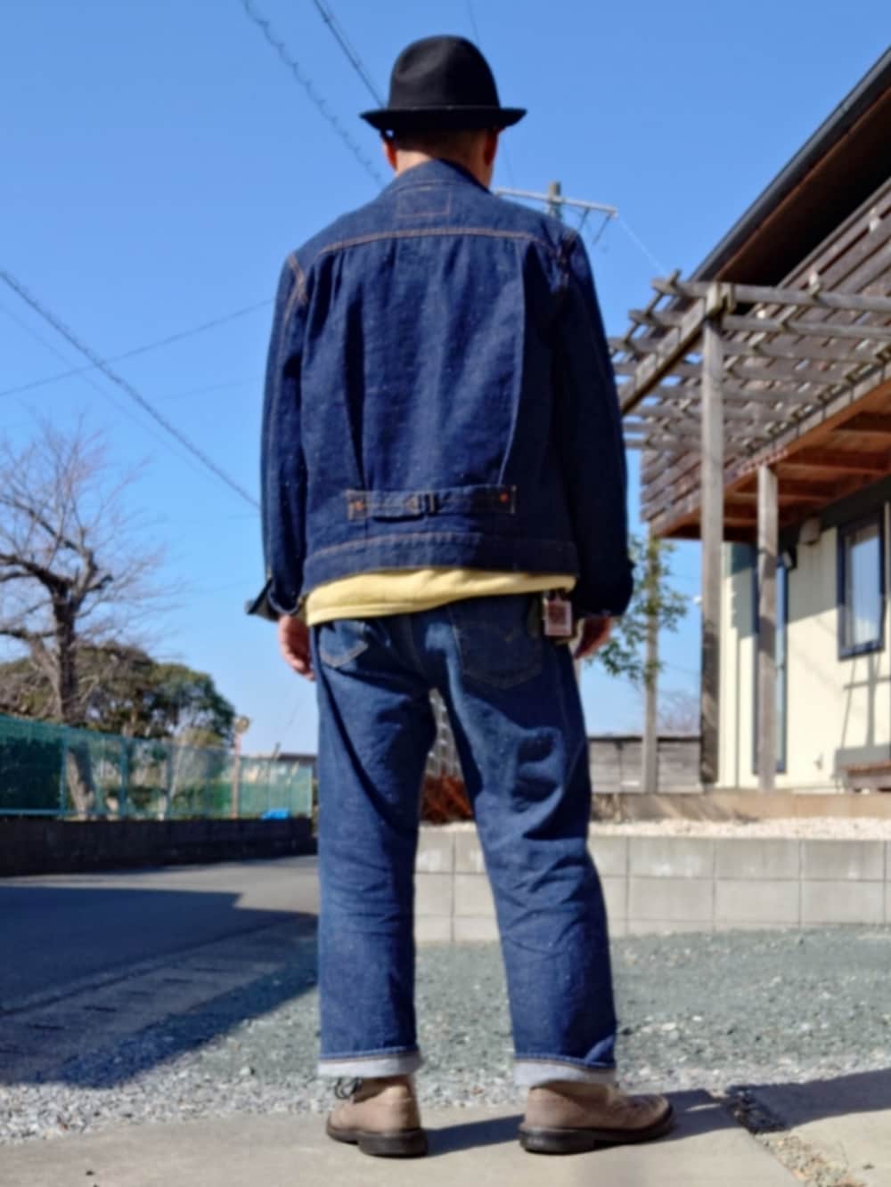 イエロー系のスウェット、ブルー系のデニムジャケット、ブルー系のデニムパンツを着用したメンズの冬コーディネートの2枚目の写真