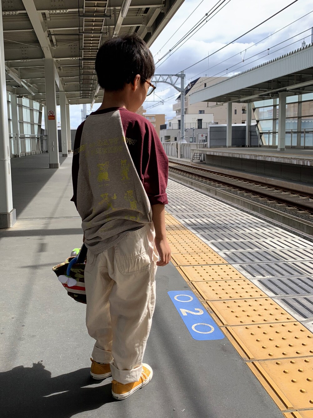 グレー系のTシャツ/カットソー、ホワイト系のパンツ、イエロー系のスニーカーを着用したキッズの秋コーディネートの3枚目の写真