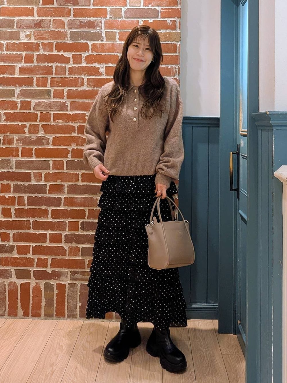 ブラック系のブーツ、その他のスカート、グレー系のショルダーバッグを着用したレディースの冬コーディネートの2枚目の写真