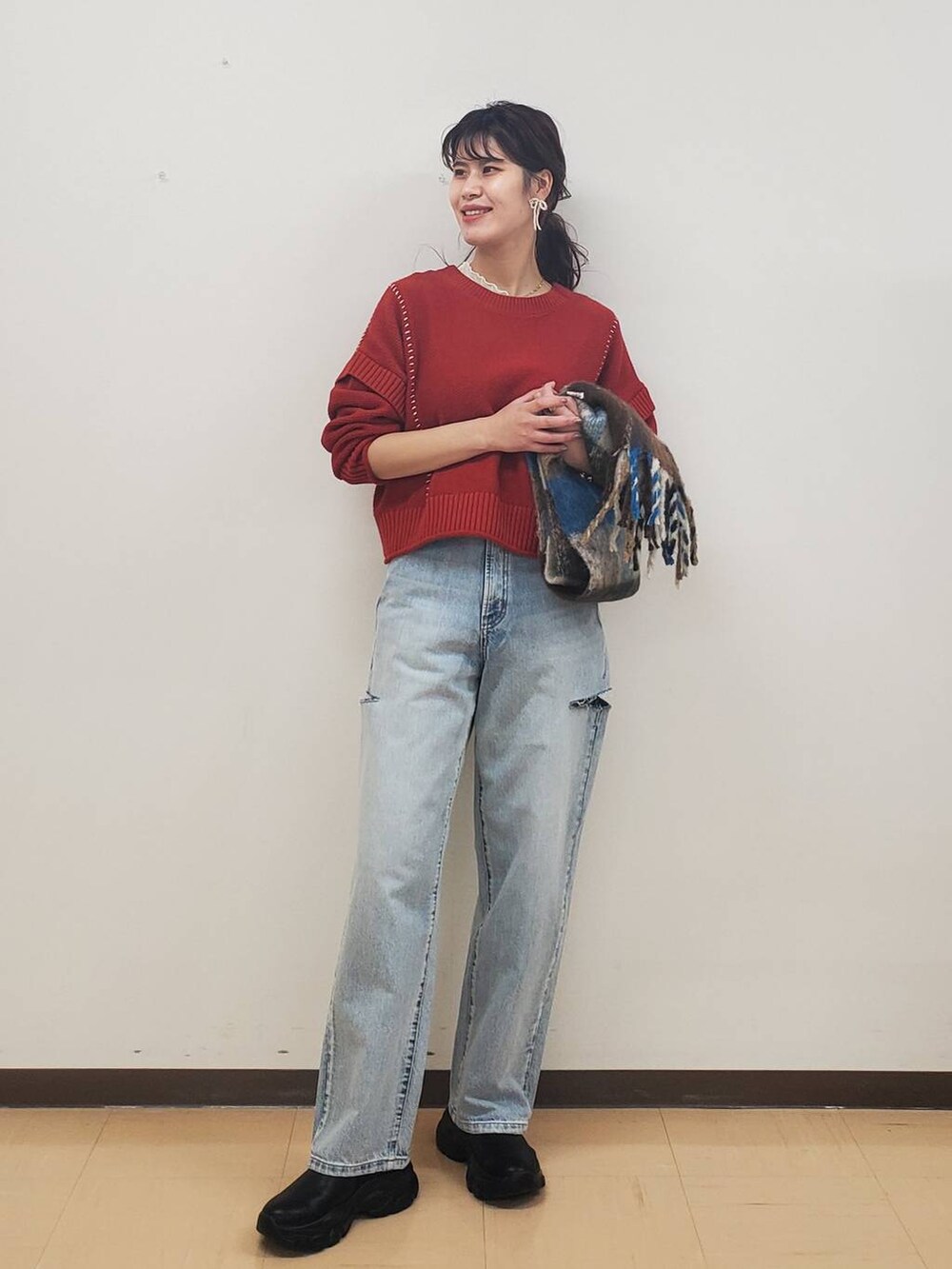 ブルー系のデニムパンツ、レッド系のTシャツ/カットソー、ブラック系のブーツを着用したレディースの秋コーディネートの2枚目の写真