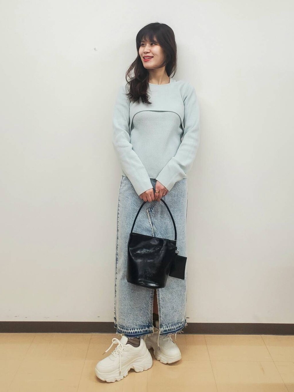 ブルー系のスカート、ホワイト系のスニーカー、ブラック系のトートバッグを着用したレディースの冬コーディネートの2枚目の写真