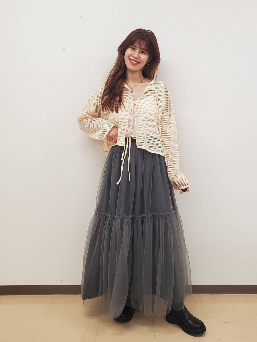 ホワイト系のキャミソール、ホワイト系のカーディガン/ボレロ、ブラック系のブーツを着用したレディースの秋コーディネートの2枚目の写真