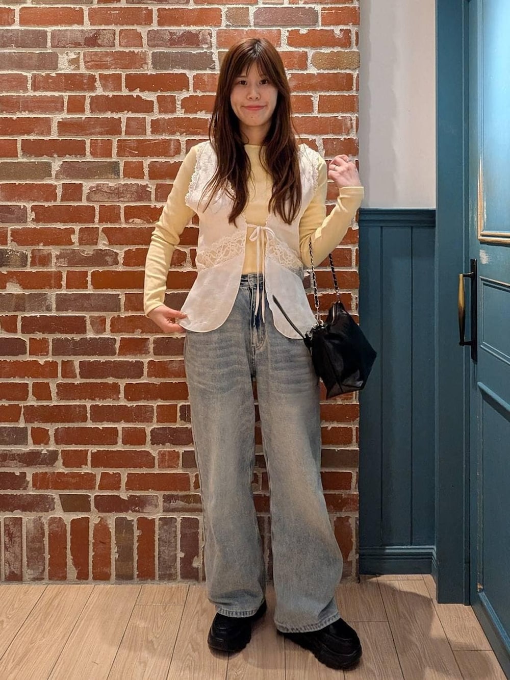 ブルー系のデニムパンツ、ブラック系のショルダーバッグ、ブラック系のローファーを着用したレディースの冬コーディネートの2枚目の写真