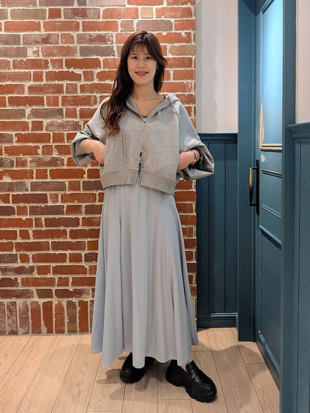 グレー系のパーカー、ブラック系のローファー、ホワイト系のタンクトップを着用したレディースの春コーディネートの2枚目の写真