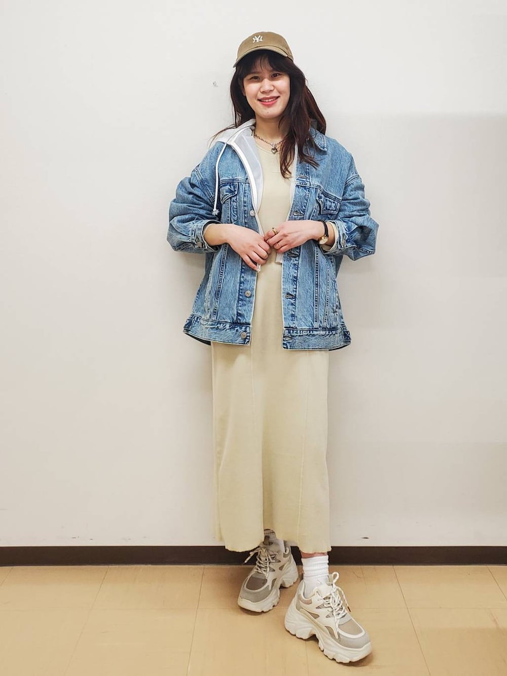 ブルー系のデニムジャケット、ベージュ系のスニーカー、ホワイト系のパーカーを着用したレディースの春コーディネートの2枚目の写真