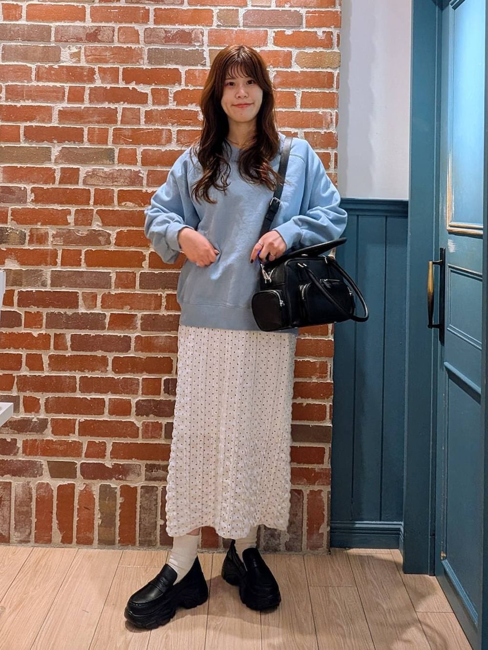 ブラック系のボストンバッグ、ブラック系のローファー、ホワイト系のスカートを着用したレディースの冬コーディネートの2枚目の写真