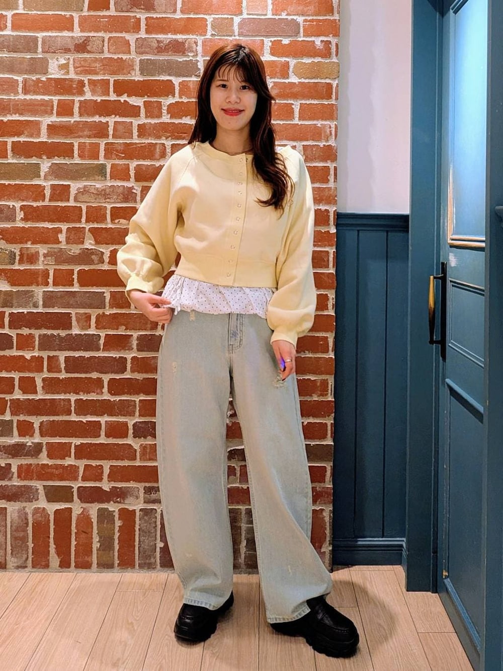 ブルー系のデニムパンツ、ブラック系のローファー、イエロー系のスウェットを着用したレディースの冬コーディネートの2枚目の写真