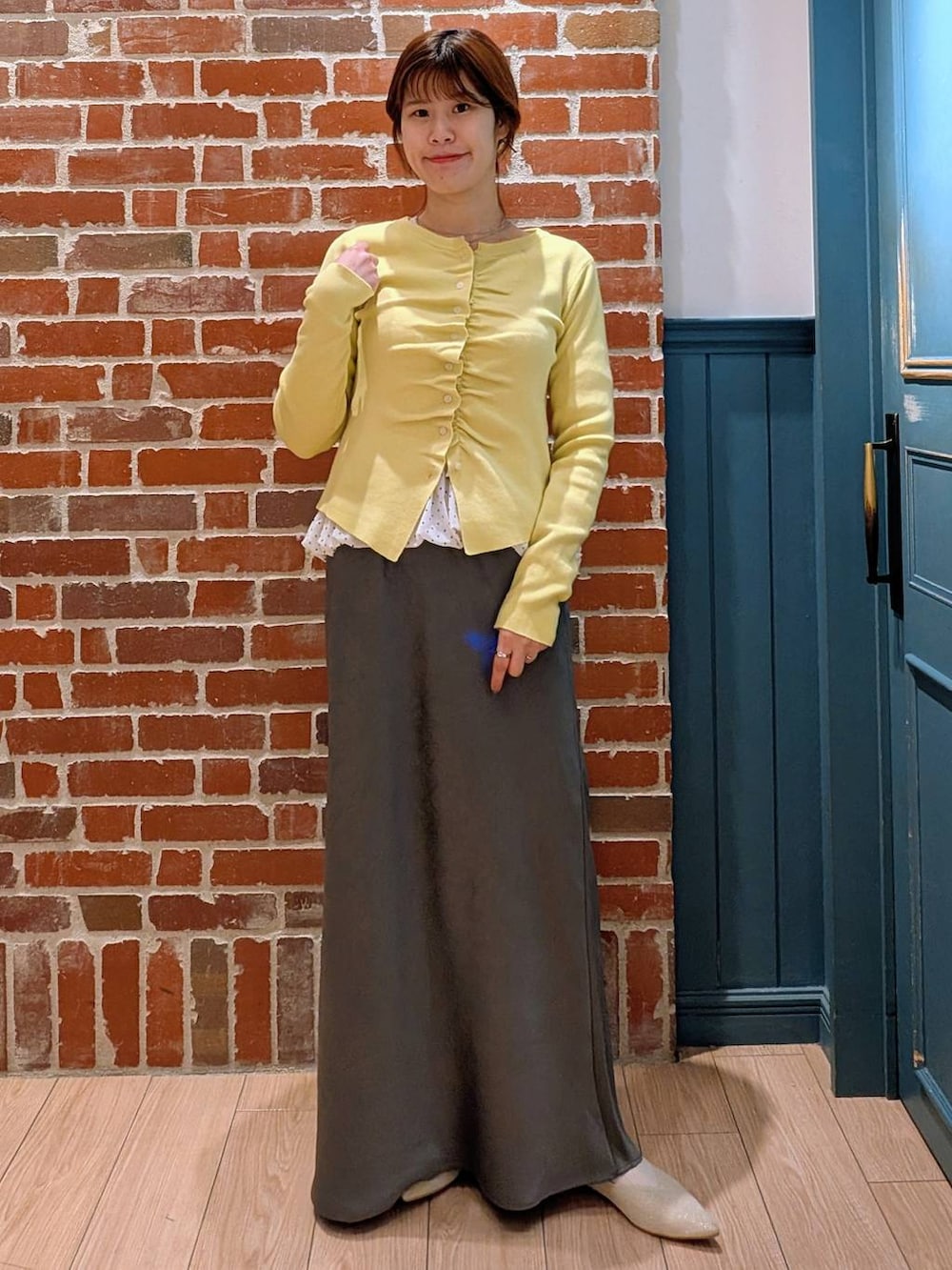 グレー系のスカート、ホワイト系のパンプス、ホワイト系のTシャツ/カットソーを着用したレディースの春コーディネートの2枚目の写真