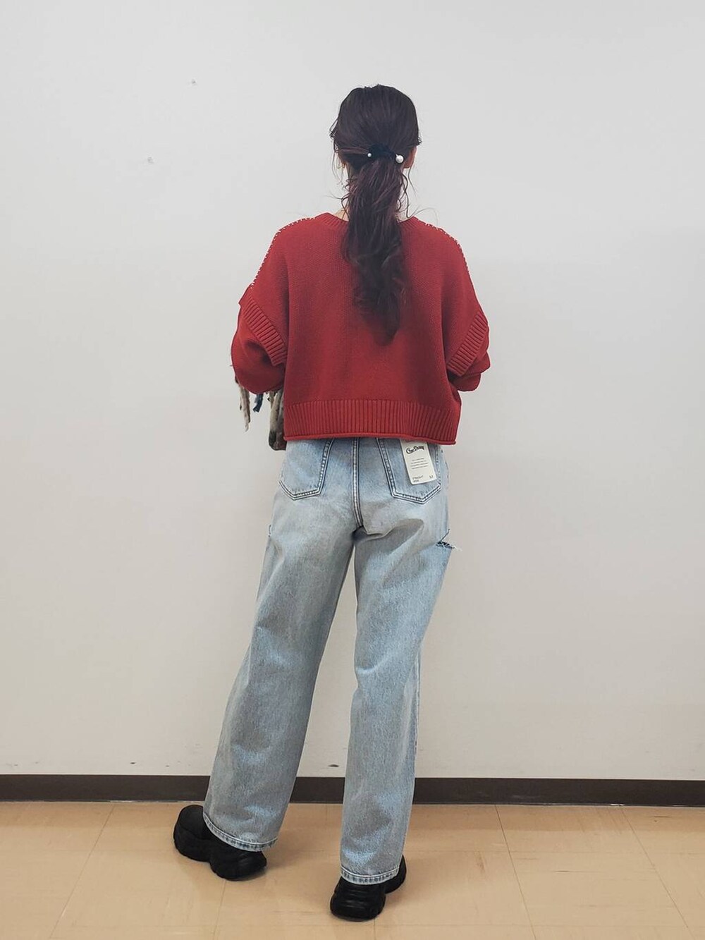 ブルー系のデニムパンツ、レッド系のTシャツ/カットソー、ブラック系のブーツを着用したレディースの秋コーディネートの3枚目の写真