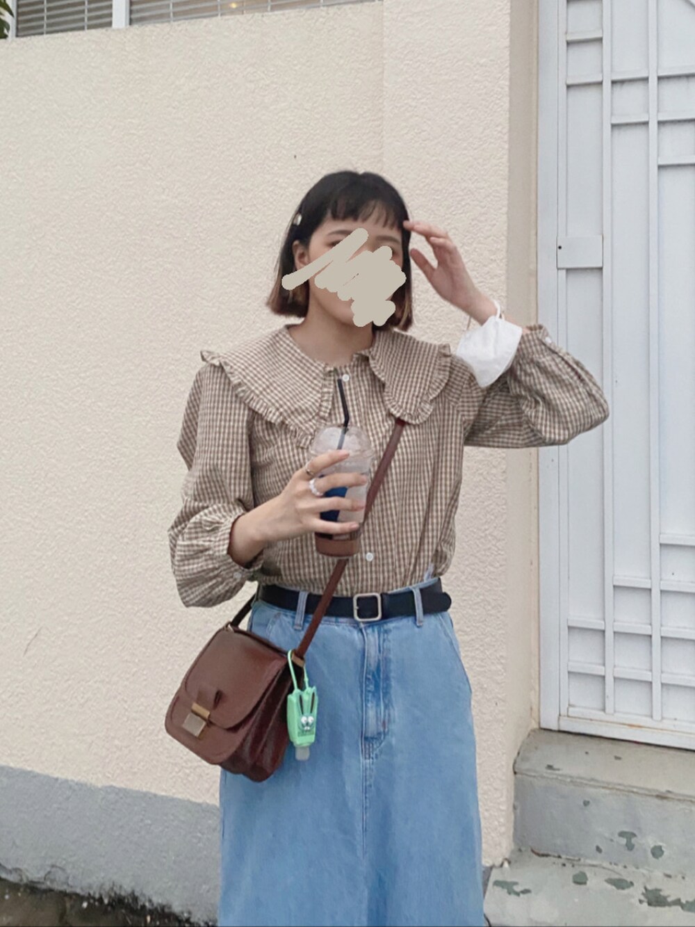 ブルー系のデニムスカート、ブラウン系のシャツ/ブラウス、ブラウン系のショルダーバッグを着用したレディースの春コーディネートの2枚目の写真