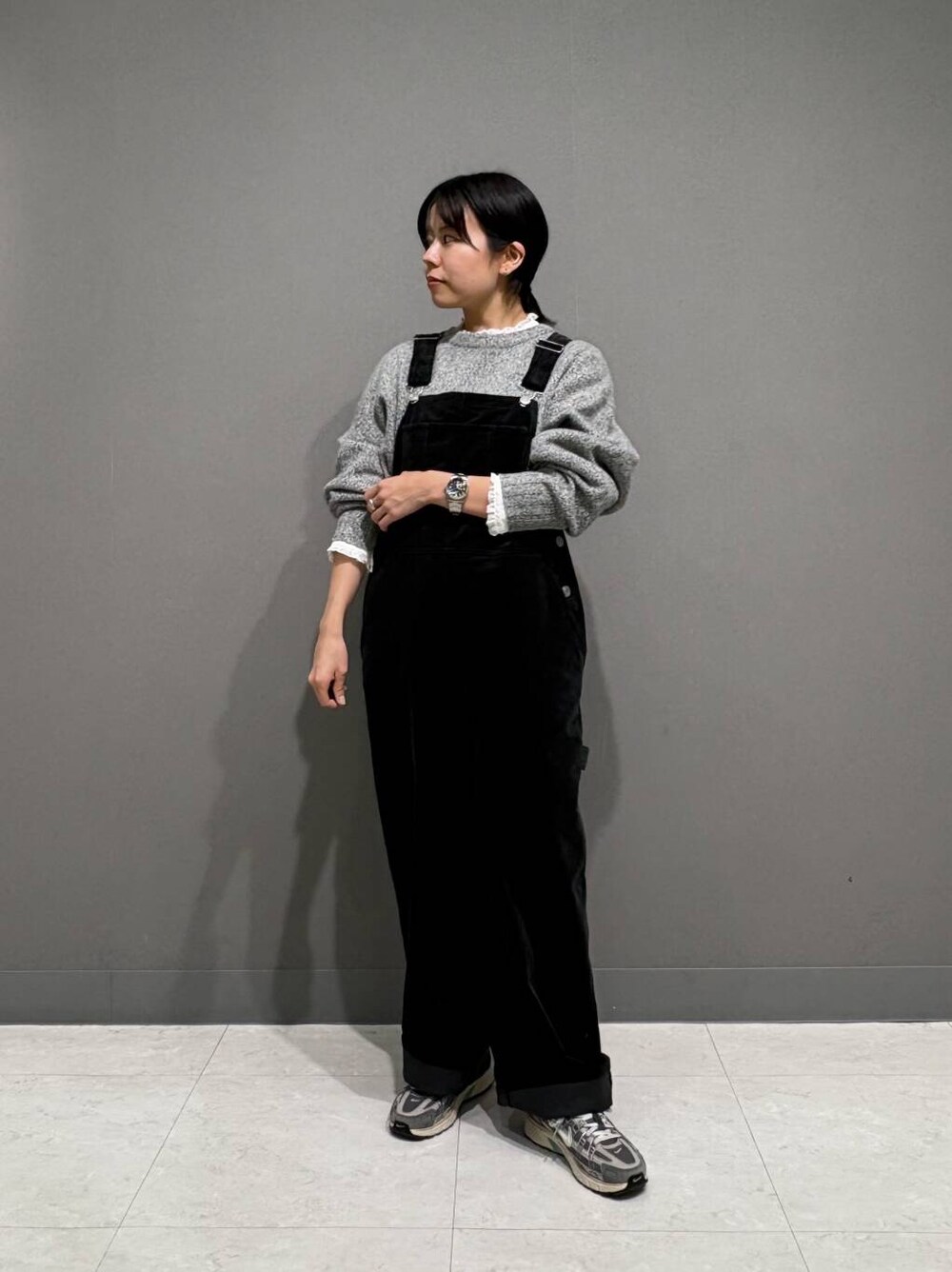 グレー系のニット/セーター、ホワイト系のシャツ/ブラウス、ブラック系のサロペット/オーバーオールを着用したレディースの冬コーディネートの2枚目の写真