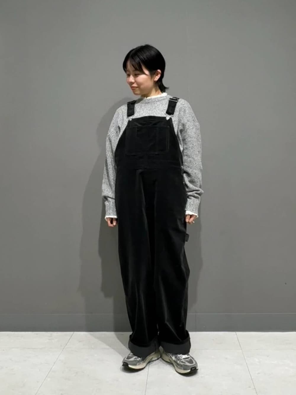 グレー系のニット/セーター、ホワイト系のシャツ/ブラウス、ブラック系のサロペット/オーバーオールを着用したレディースの冬コーディネートの3枚目の写真