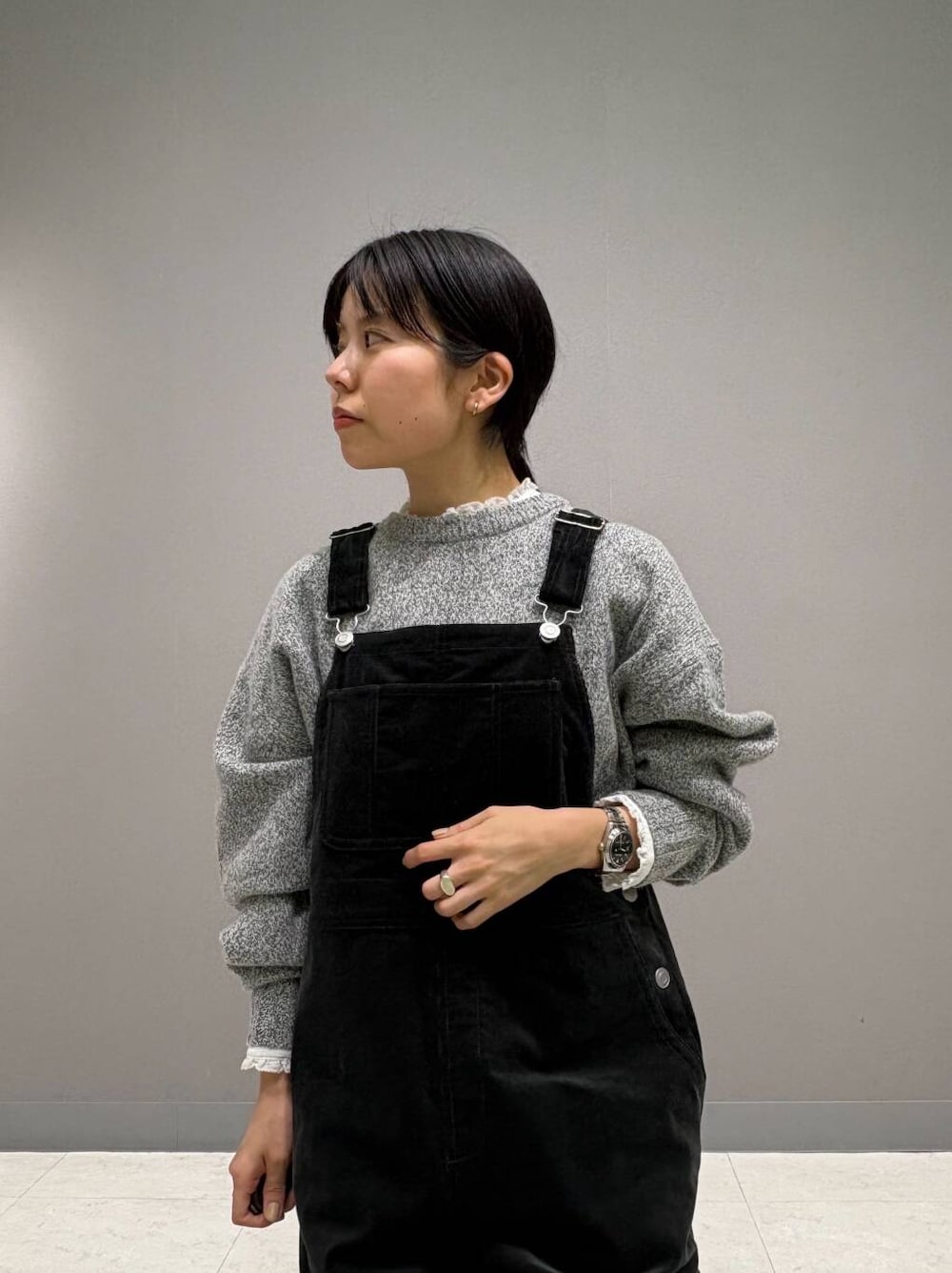 グレー系のニット/セーター、ホワイト系のシャツ/ブラウス、ブラック系のサロペット/オーバーオールを着用したレディースの冬コーディネートの5枚目の写真