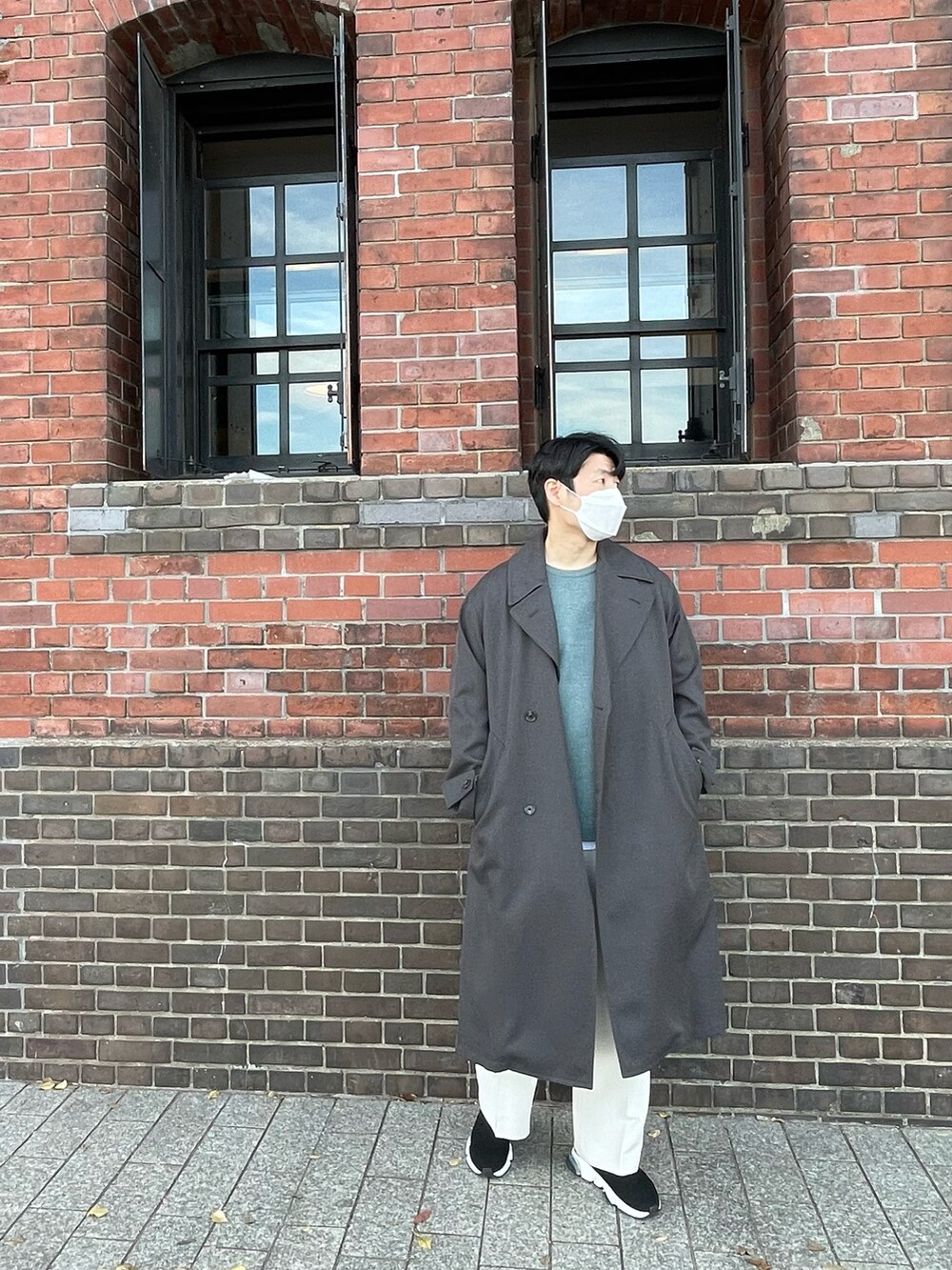 グリーン系のニット/セーター、グレー系のトレンチコート、ブラック系のシューズを着用したメンズの冬コーディネートの2枚目の写真