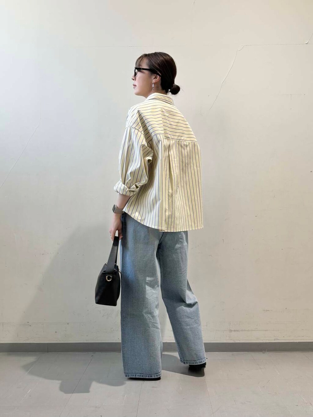 ブラック系のその他シューズ、ブルー系のデニムパンツ、イエロー系のシャツ/ブラウスを着用したレディースの冬コーディネートの4枚目の写真