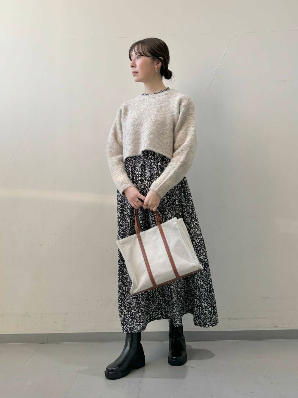 ブラック系のブーツ、ベージュ系のトートバッグ、ブラック系のワンピースを着用したレディースの秋コーディネートの2枚目の写真