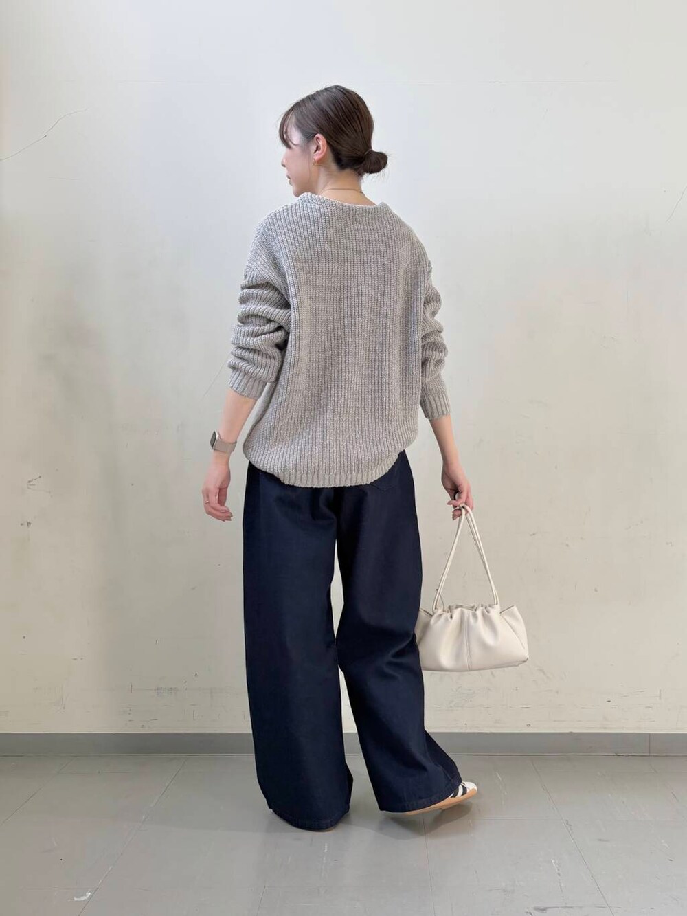 ブルー系のデニムパンツ、ホワイト系のショルダーバッグ、グレー系のニット/セーターを着用したレディースの春コーディネートの4枚目の写真