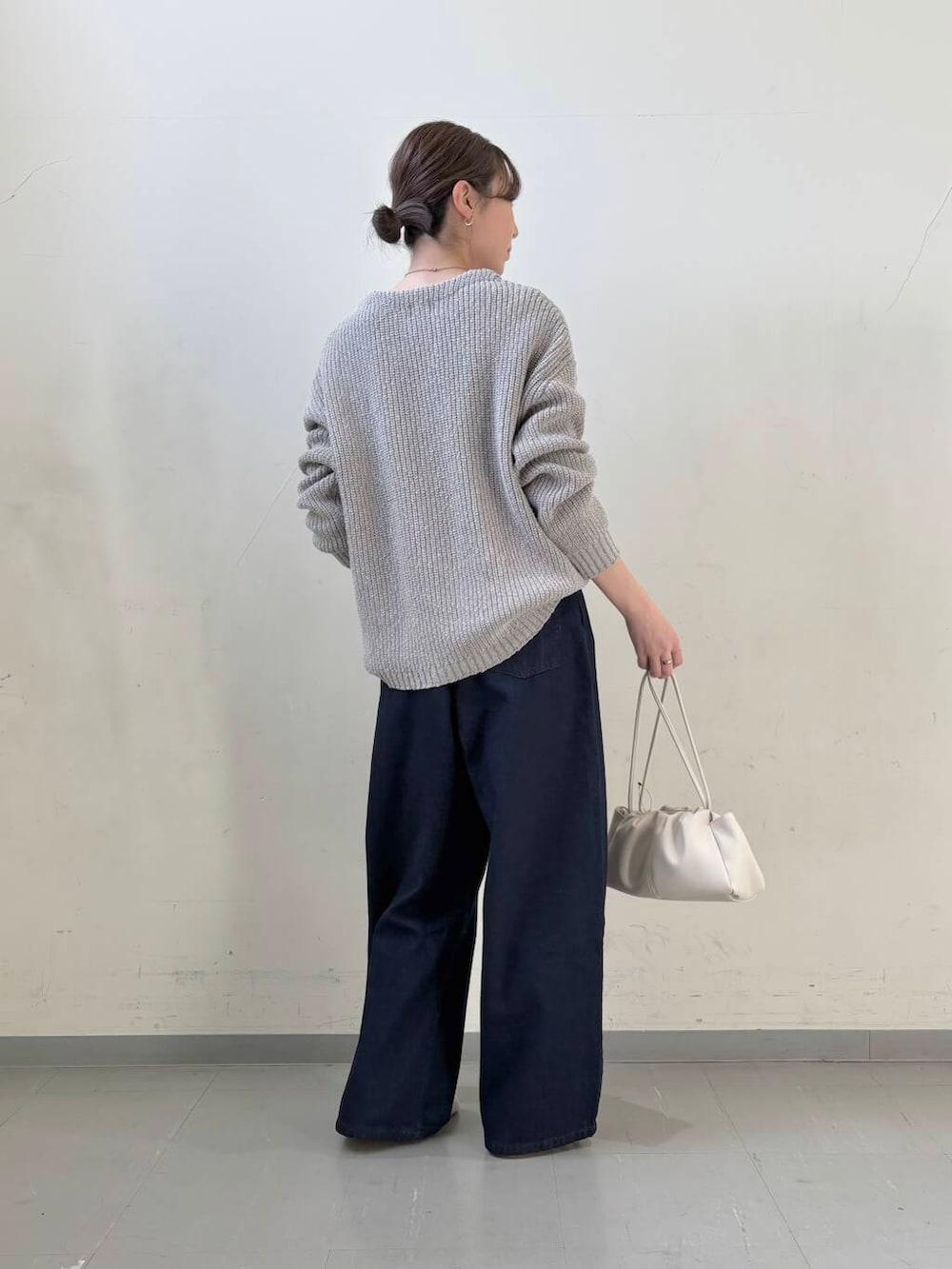 ブルー系のデニムパンツ、ホワイト系のショルダーバッグ、グレー系のニット/セーターを着用したレディースの春コーディネートの5枚目の写真